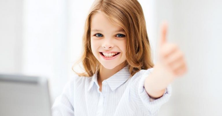 a little girl smiling with her arm outstretched and thumb up