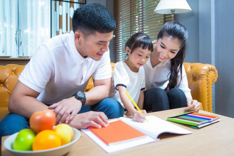 a mother and father observing their child writing in a notebook